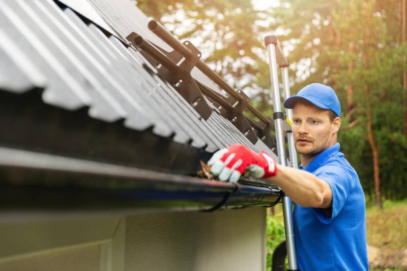 A Happy Valley Exteriors service technician cleaning a gutter