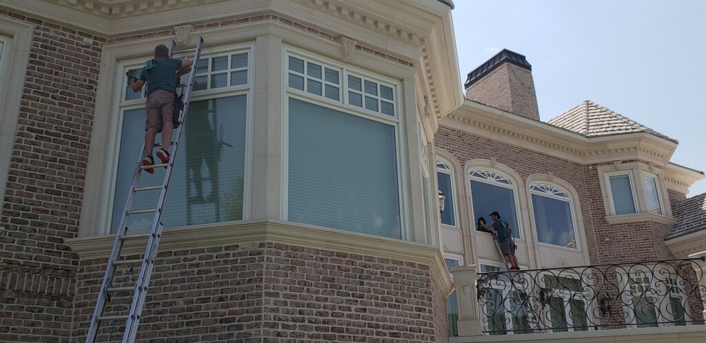 Two employees window cleaning while standing on ladders